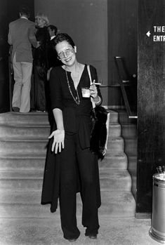 an old photo of a woman standing on the stairs with a drink in her hand