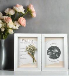 two white frames with flowers in them on a table next to a vase and wall