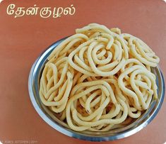 a metal bowl filled with noodles on top of a table