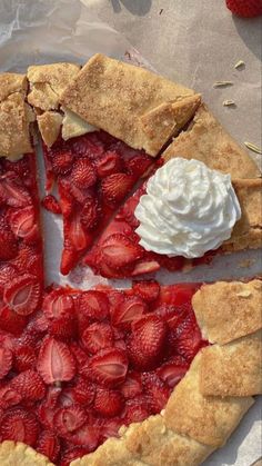 a pie with strawberries and whipped cream on top is cut in half to show the filling