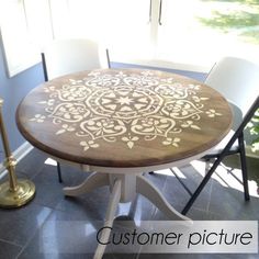 a round table with white chairs and a candle on the floor in front of a window