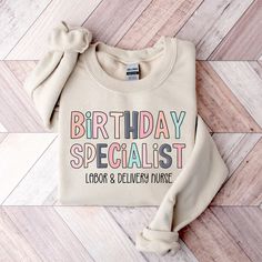 a sweater with the words birthday specialist on it sitting on a wooden floor next to a pair of scissors