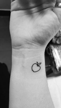 an apple tattoo on the wrist is shown in this black and white photo, it looks like