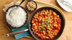 a pan filled with rice and vegetables on top of a wooden tray next to other dishes