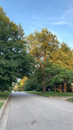 an empty street lined with trees and grass