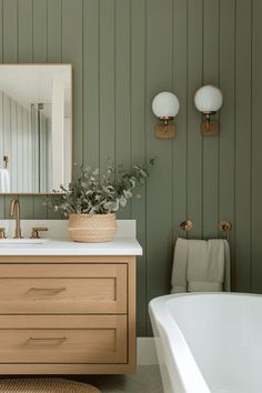 a bathroom with green painted walls and wooden cabinet, white bathtub and mirror on the wall