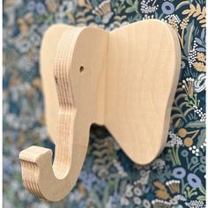 an elephant shaped wooden toy hangs on the wall in front of a blue floral background