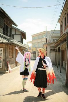 two women dressed in costume walking down a street together, one holding her hand out to the side