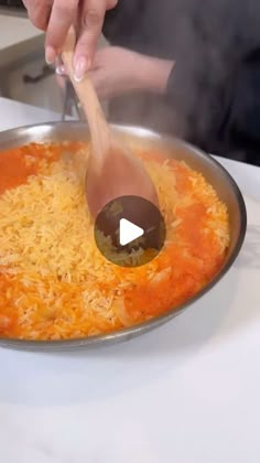 a person stirring food in a pan with a wooden spoon on the stove top,