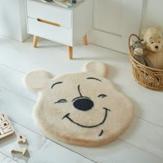 a teddy bear rug with a smiling face on the floor next to other stuffed animals