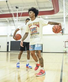 two young men playing basketball in an indoor gym with one holding a ball and the other dribble