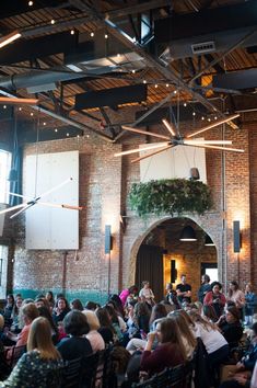 a large group of people are sitting in the middle of a room with exposed ceilings