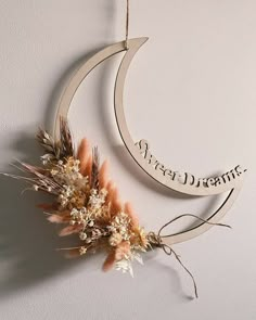 a wooden sign hanging from the side of a wall next to dried flowers and leaves