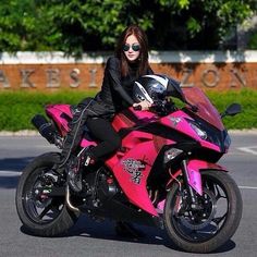 a woman sitting on top of a pink motorcycle