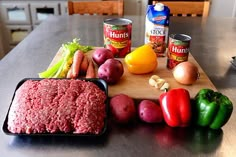 an assortment of food sitting on top of a cutting board next to vegetables and meat