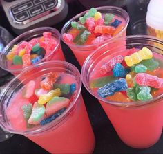 four cups with gummy bears in them sitting on a table next to a blender