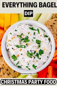 a white bowl filled with dip surrounded by veggies and crackers on the side