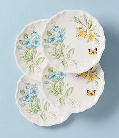 three white plates with blue flowers and butterflies on the rims, one is yellow