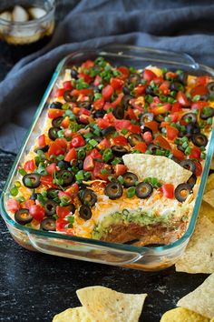 a glass casserole dish filled with black olives, tomatoes and green peppers