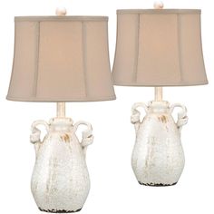 two white vases with beige lamps on them