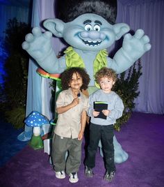 two children standing in front of a cartoon character