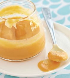 a small glass jar filled with orange custard on top of a white plate