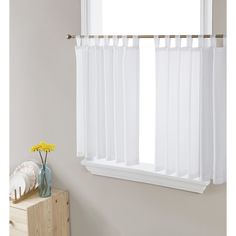 a window with white sheer curtains and yellow flowers