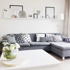 a living room filled with lots of furniture next to a white table and wall mounted pictures