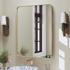 a bathroom with a sink, mirror and vase on the counter in front of it