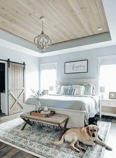 a dog laying on top of a rug next to a bed in a room with white walls