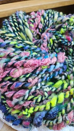 a pile of multicolored yarn sitting on top of a wooden table next to a window