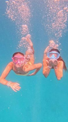 two people wearing goggles and snorkels are swimming in the blue water