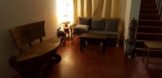 a living room filled with furniture next to a stair case and window covered in yellow curtains