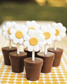 small cupcakes with white and yellow flowers on them sitting on a checkered tablecloth