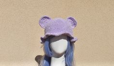 a white mannequin head wearing a purple crocheted hat with bear ears