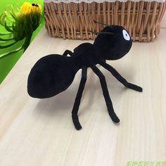 a black ant bug sitting on top of a wooden table next to a basket with flowers