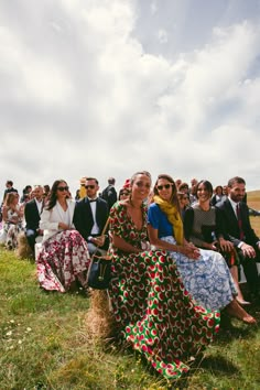 two women sitting on hay bales in front of a group of people