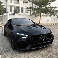 a black mercedes amg coupe parked in front of a white building on a brick road