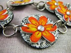 an orange and white flower bracelet on a gray surface with silver links attached to it