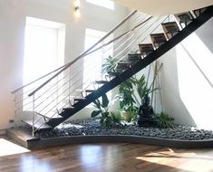 an indoor stair case with plants and rocks on the bottom, in front of a window