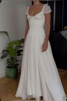 a woman in a white wedding dress standing next to a plant