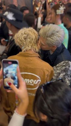 two people are kissing each other in front of a group of people taking pictures with their cell phones