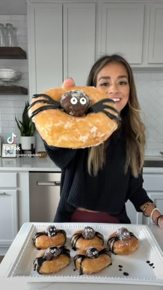 a woman holding up a doughnut with a spider on it