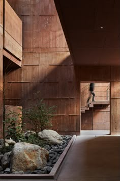 an empty room with rocks and plants in the foreground, next to a staircase