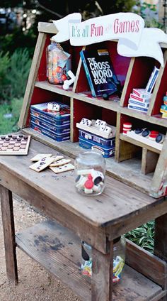 a wooden table topped with lots of books and snacks on it's sides next to a garden