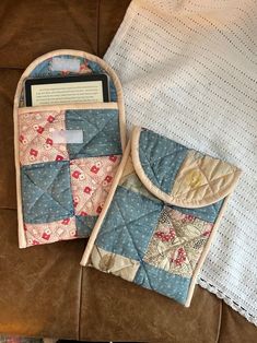 two pieces of quilt sitting on top of a couch next to an electronic device case