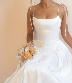 a woman in a white wedding dress holding a bouquet with flowers on the bottom of it