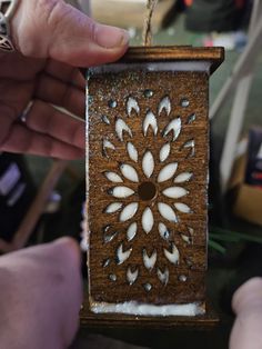 a person holding a small wooden box with white designs on it