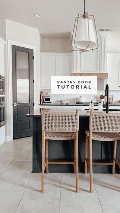 two wicker chairs sit at an island in the middle of a kitchen with black and white cabinets