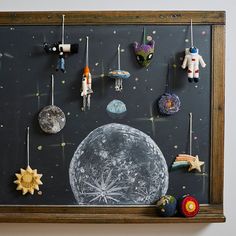 a chalkboard with ornaments hanging from it's sides and an image of the moon